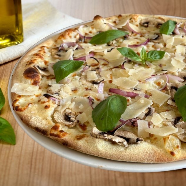 Pizza blanche Giulia Bianca garnie de mozzarella fior di latte, champignons frais, oignons rouges, basilic et parmesan italien sur pâte fine, servie chez Gino & Giulia à Jacou.