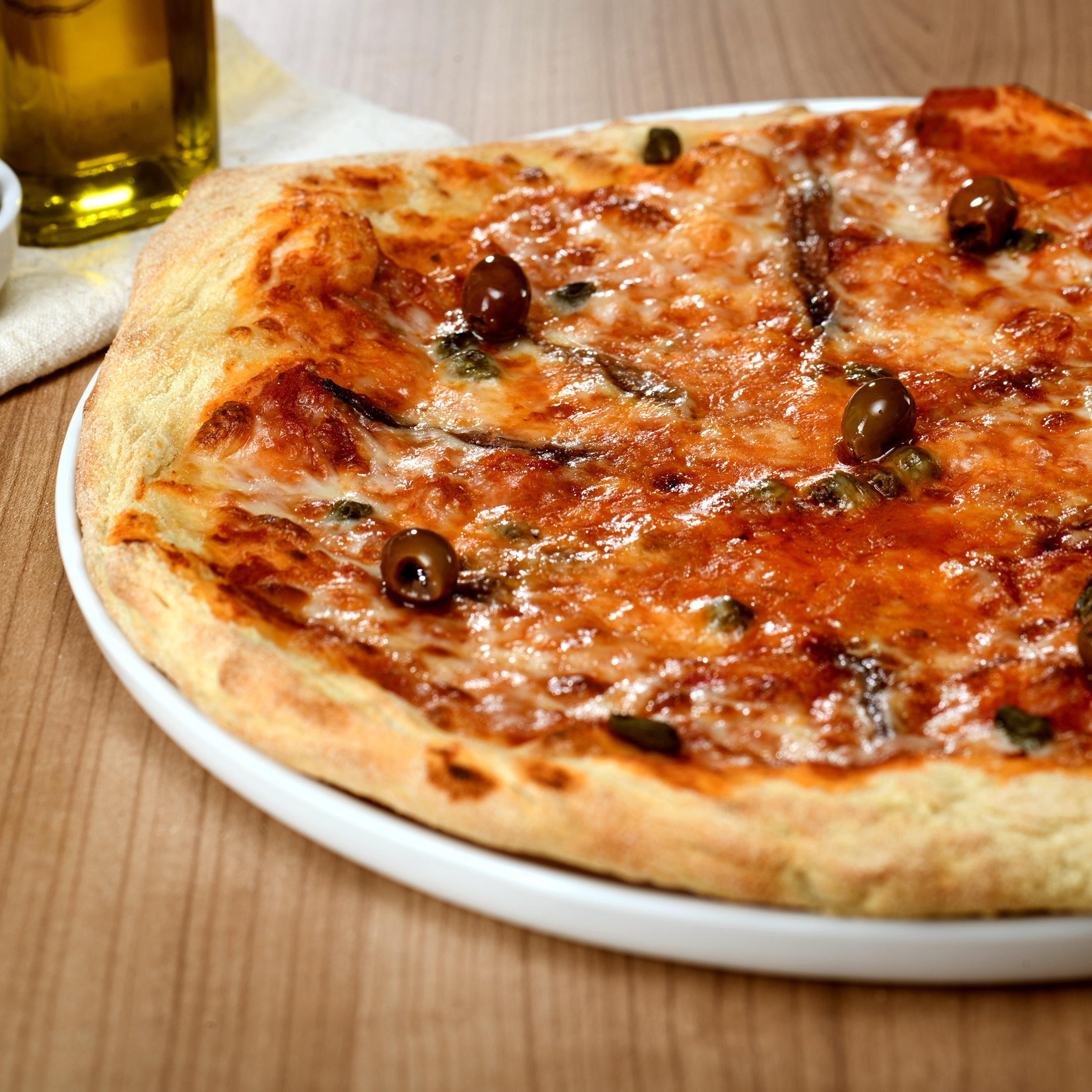 Pizza Napoletana avec sauce tomate, mozzarella Fior di Latte, anchois, câpres et olives – pizza à emporter ou en livraison